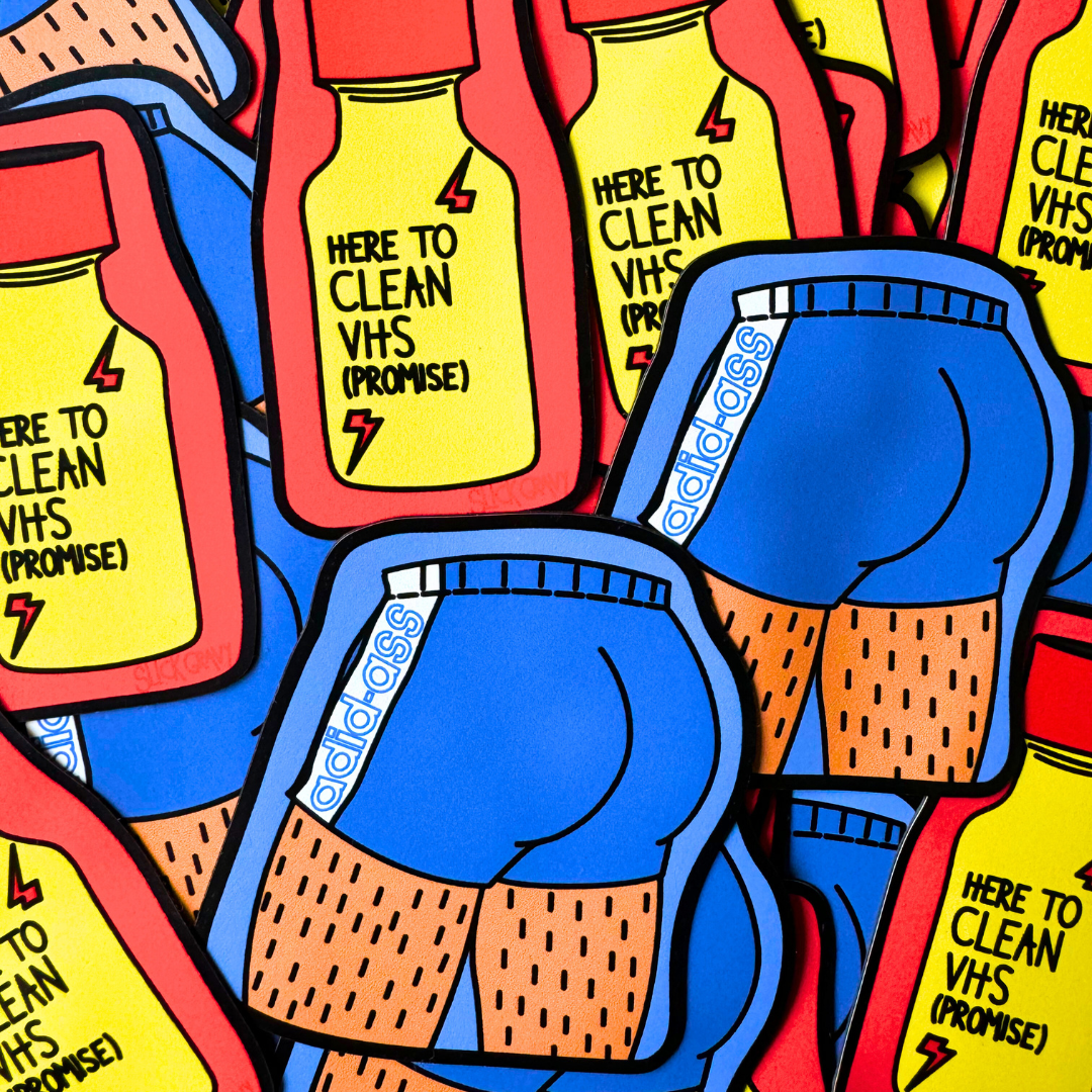 A magnet shaped like a red and yellow poppers bottle with the text 'HERE TO CLEAN VHS (Promise)' on it and a blue adid-ass magnet on a blue butt.