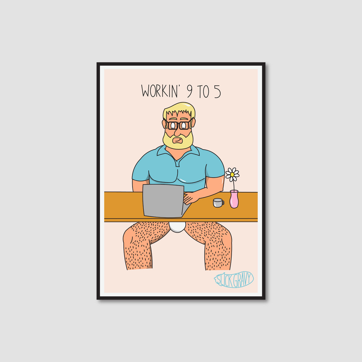A framed art print with a white border on a light peach background. The print shows a cartoon man with blond hair and a beard sitting at a desk with a laptop, wearing only a blue shirt, with the text 'WORKIN' 9 TO 5' above him.