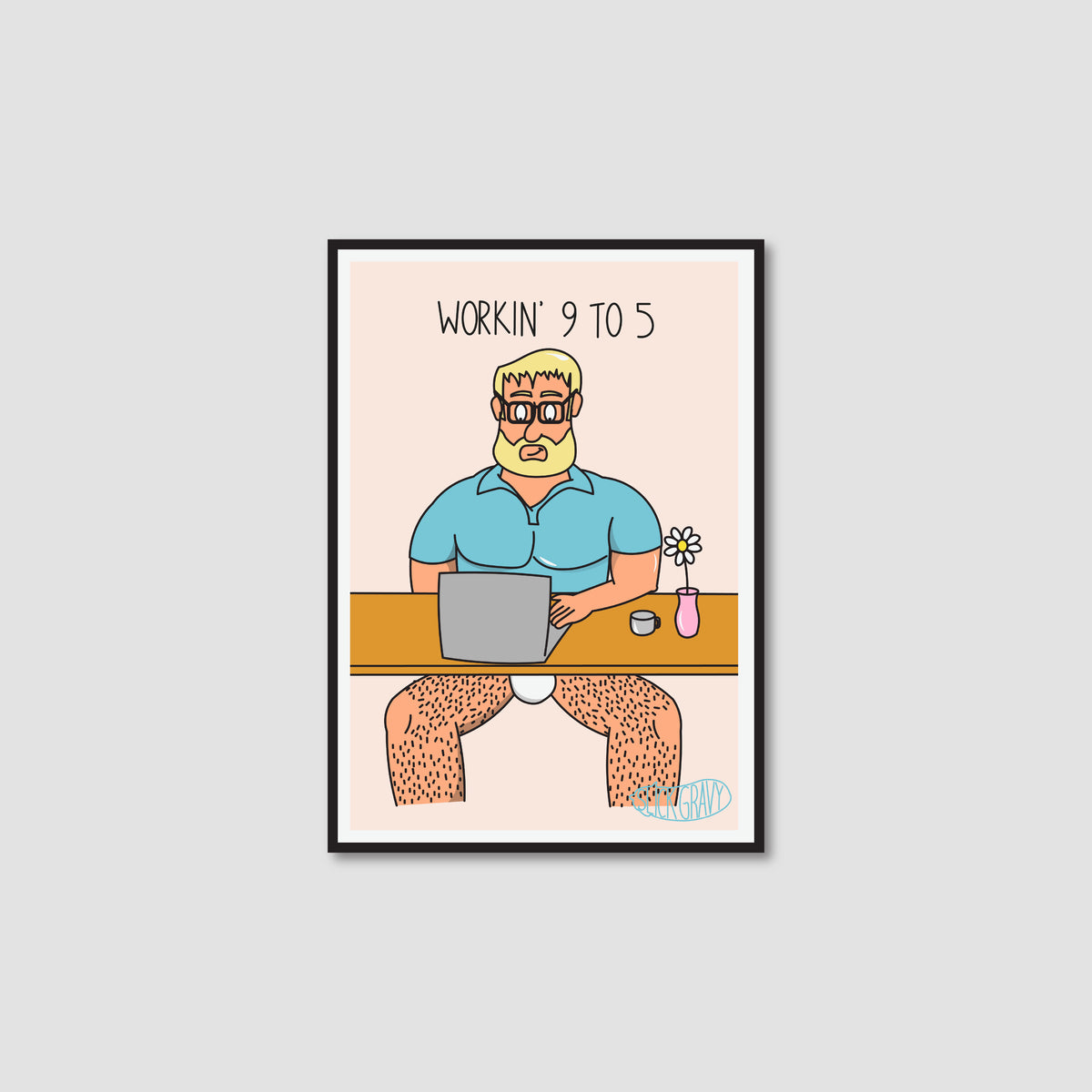 A framed art print with a white border on a light peach background. The print shows a cartoon man with blond hair and a beard sitting at a desk with a laptop, wearing only a blue shirt, with the text 'WORKIN' 9 TO 5' above him.